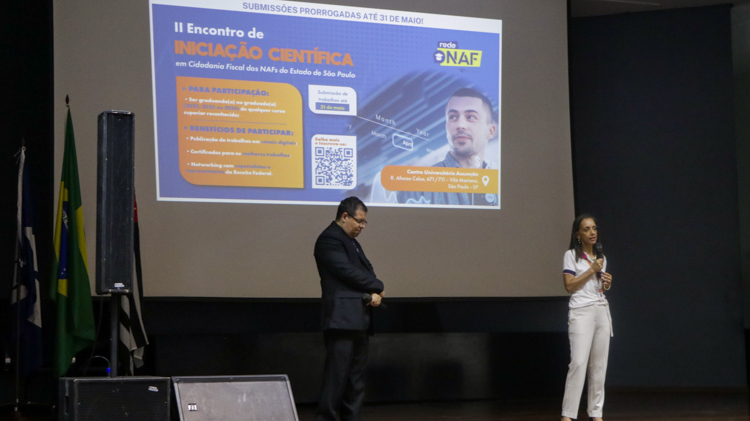 Prof.ª Dr.ª Edineide Maria e Marcos Gregório Borges, ex-aluno do Assunção e representante da Superintendência da Receita Federal, apresentando o II Encontro de Iniciação Científica em Cidadania Fiscal dos NAFs do Estado de São Paulo.