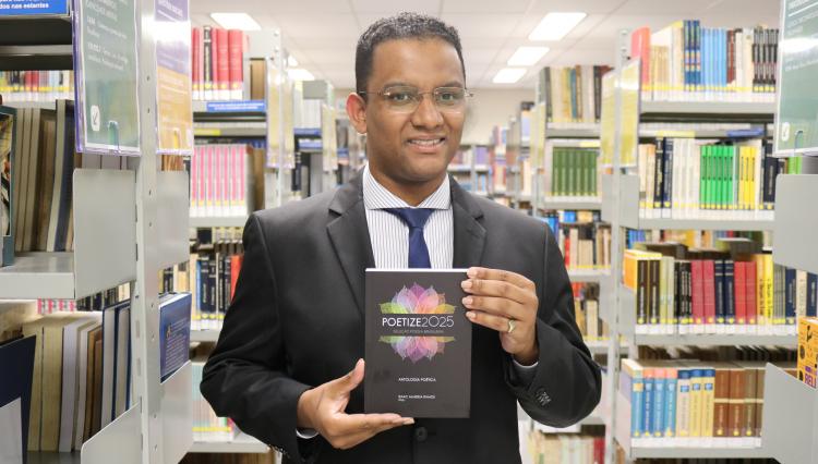 Aluno Alex Rodrigo, segurando o livro Poetize 2025 na Biblioteca do Assunção.